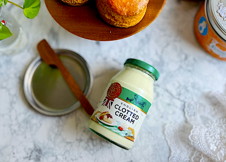 テーブルに転がったコストコのクロテッドクリーム、シルバーのトレイ、バターナイフ