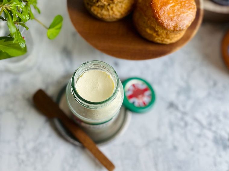 コストコのクロテッドクリームの蓋を開けて横に置いたところ、バターナイフ、スコーン