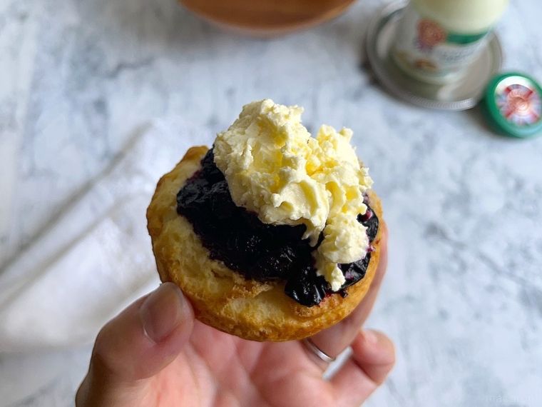 コストコのクロテッドクリームとジャムをのせたスコーンを手に持ったところ