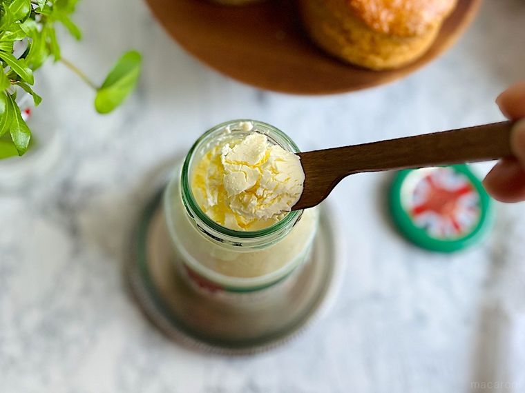 蓋を開けたコストコのクロテッドクリームにバターナイフを入れてすくい上げているところ