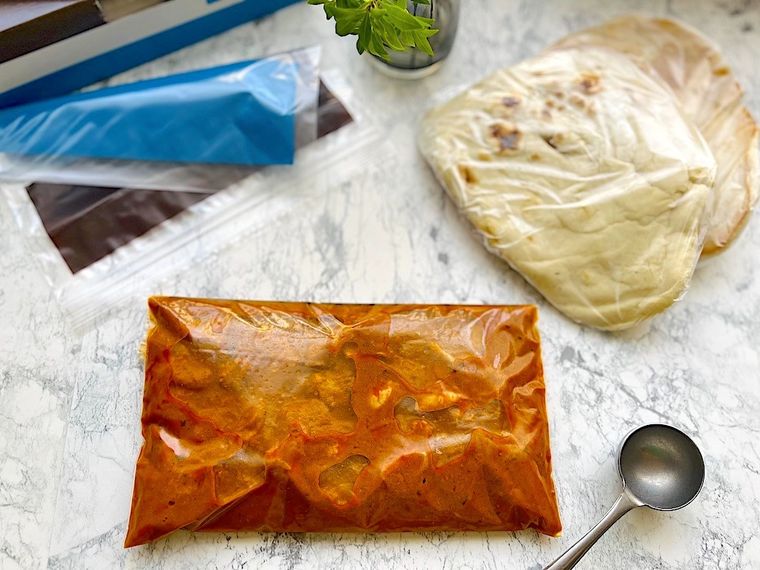 ジップ付き保存袋に入れ冷凍するコストコのバターチキンカレー、ラップに包んだナン、保存袋、スプーン