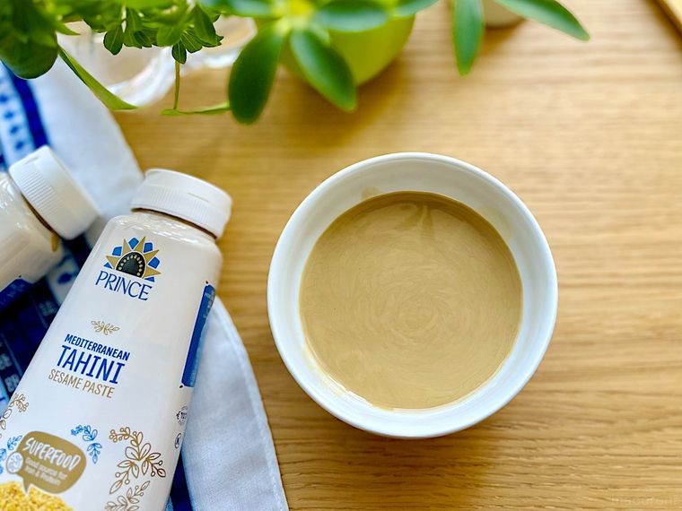 白い小皿になみなみと入ったコストコのタヒニゴマペースト、横に置かれたたひにのボトル
