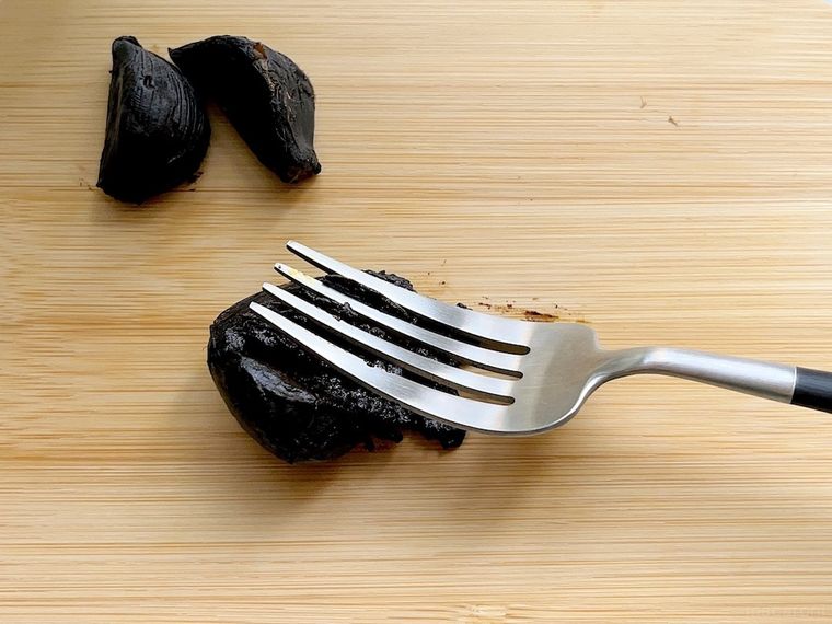 コストコの黒にんにくをウッドボードに出してフォークの背で潰しているところ
