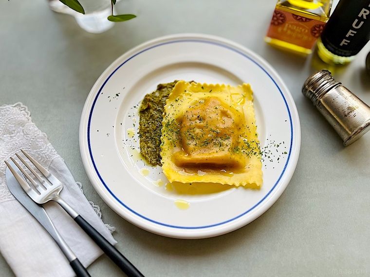 白いプレートに盛り付けてソースを添えた1枚のコストコジャイアントラビオリ、カトラリー、調味料