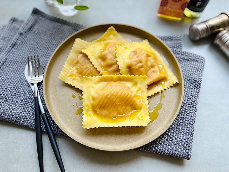 調理してプレートに盛り付けた4個のコストコジャイアントラビオリ、グレーのランチョンマット、カトラリー、調味料