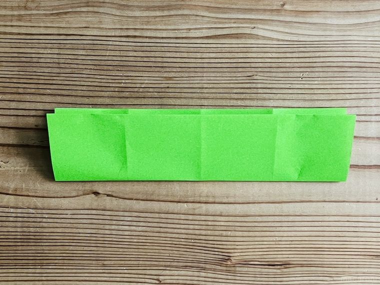 緑色の折り紙を四つ折りにした様子