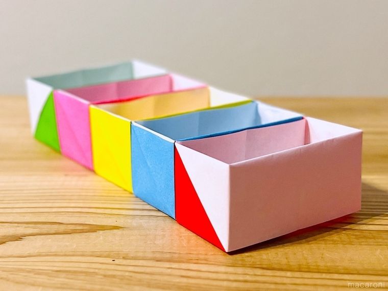 緑色、ピンク色、黄色、水色、赤色の折り紙で作った5つの箱を連結させた様子