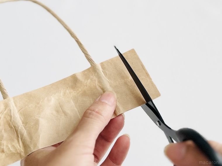 紙袋の持ち手をハサミで切っている様子