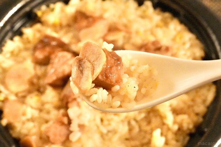 黒い容器に入ったにんにくチャーハンとフライドガーリックとチャーシューを白いれんげですくう様子