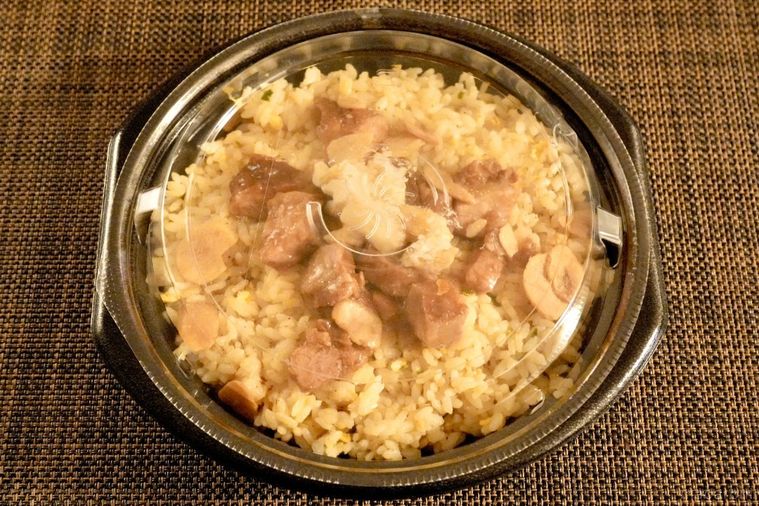 茶色いランチョンマットにのったコンビニの背脂にんにく豚チャーハンと黒い容器