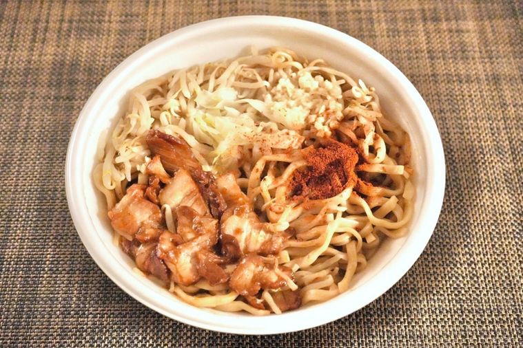 茶色いランチョンマットにのったコンビニの旨辛二郎系ラーメンが盛られた白い容器