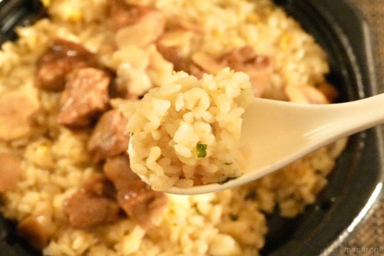 黒い容器に入ったコンビニのにんにくチャーハンを白いれんげですくう様子