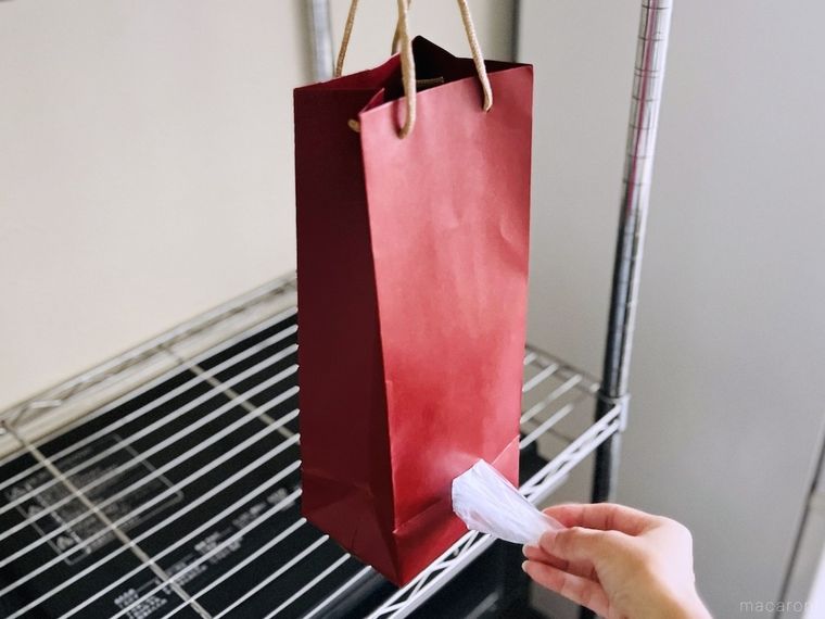 赤いワイン袋の側面に開けた穴からポリ袋を取り出している様子
