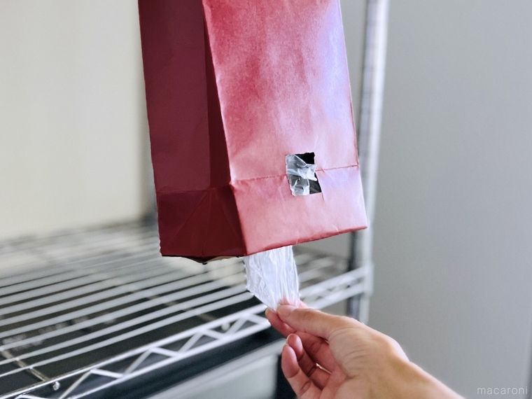 赤いワイン袋の底に開けた穴からポリ袋を取り出している様子