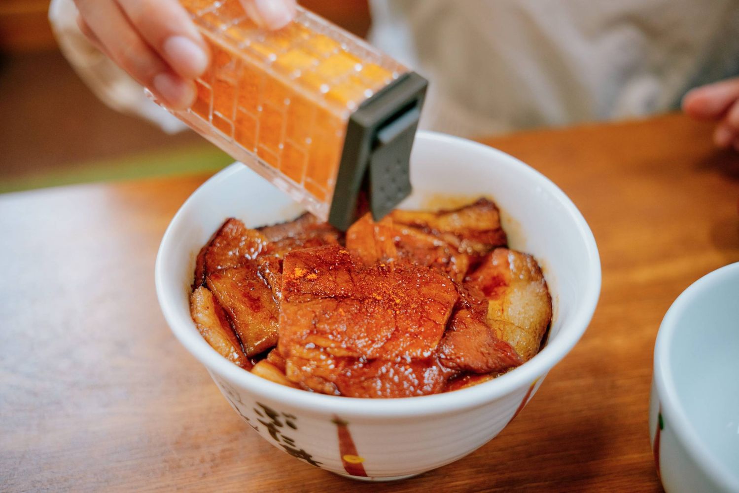 豚丼ににんにく七味をかけている様子