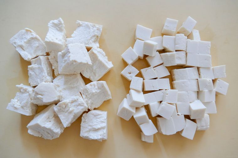 手でちぎった豆腐と小さい角切りの豆腐が並ぶまな板