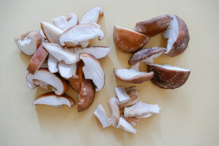 薄切りと半分に切られたしいたけとしいたけの軸が並ぶまな板