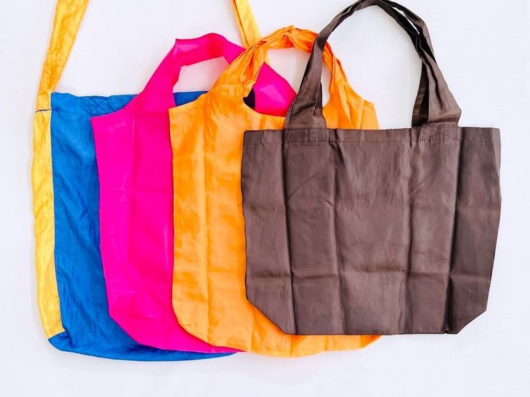 青、ピンク、オレンジ、茶色のエコバッグが並んでいる様子