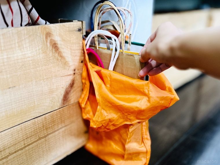 オレンジ色のエコバッグから紙袋を取り出している様子
