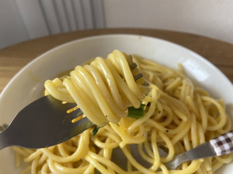 トップバリュ 大盛りカルボナーラの麺をフォークで巻きつけている