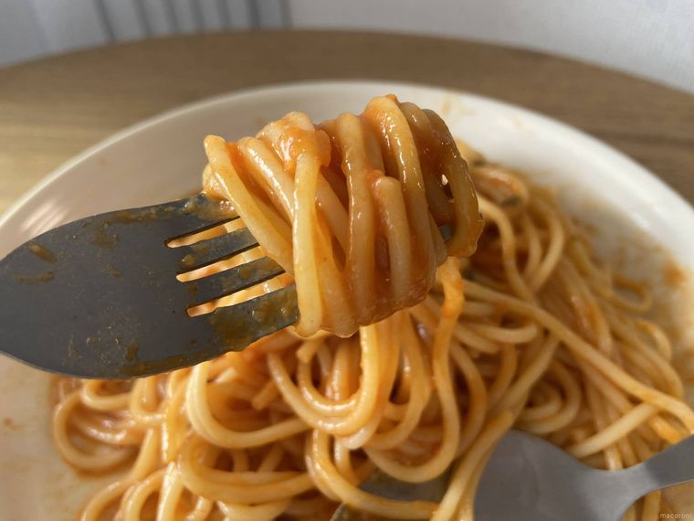 トップバリュ 大盛りかにトマトクリームの麺をフォークで巻きつけている