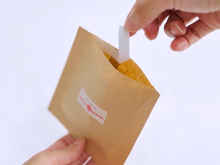 茶封筒に貼った両面テープの剥離紙を剥がしている様子