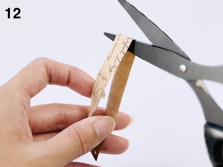 輪っかに切ったクラフト紙の封筒を、ハサミで切り開いている様子