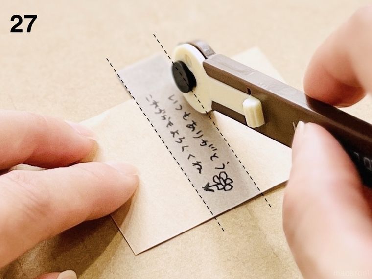 マスキングテープを貼った封筒の切れ端にミシン目カッターで切れ目を入れている様子