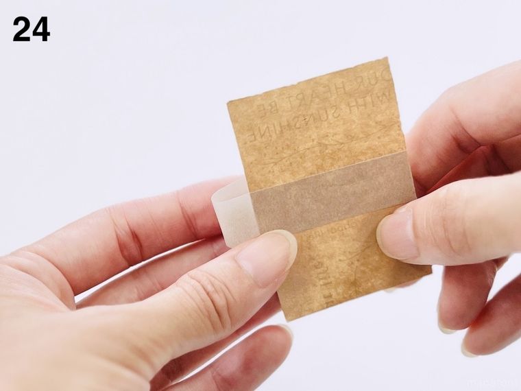 クラフト紙の封筒の切れ端にグレーのマスキングテープを貼っている様子
