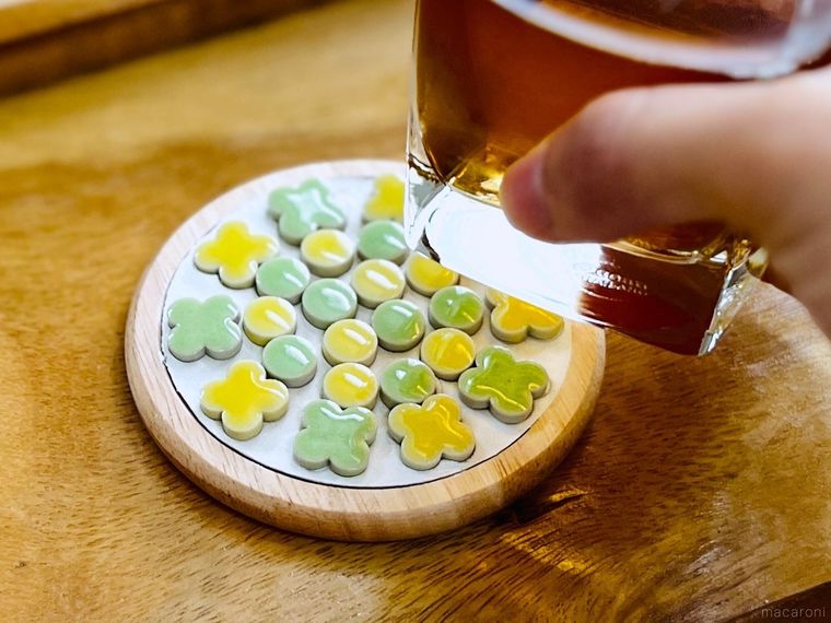 黄色と緑色のタイルがついたコースターにグラスをのせようとしている様子