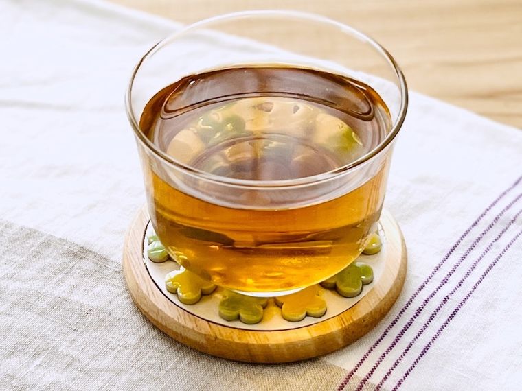 木のコースターに麦茶が入ったグラスをのせた様子