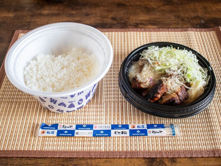 松屋でテイクアウトしたジャークチキンとごはんが木製のテーブルの上に並んでいる