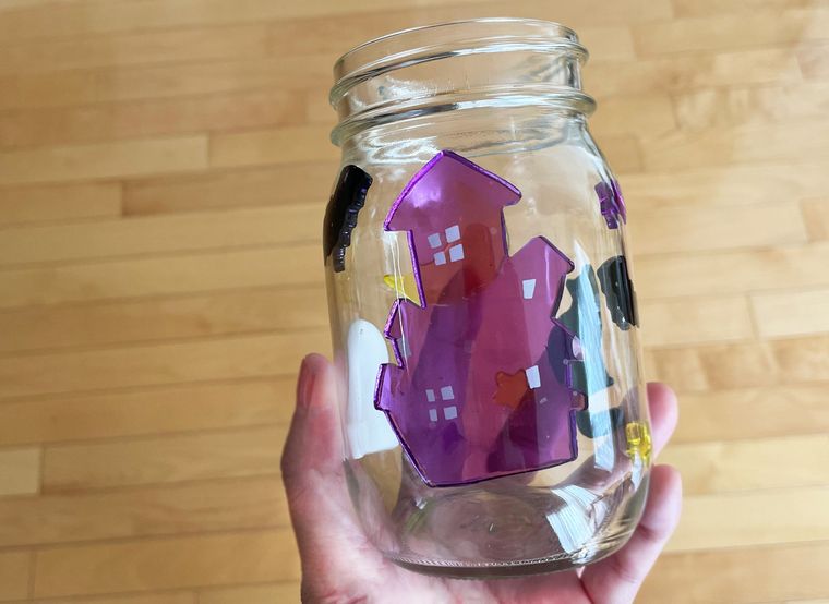 内側にシールを貼ったガラス容器を手で持っているところ