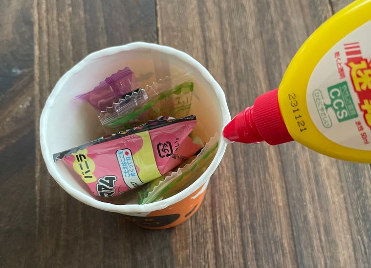 紙コップのフチにボンドを塗っている