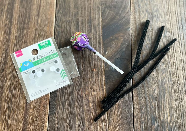 黒いモールと棒キャンディと目玉シールを並べた写真