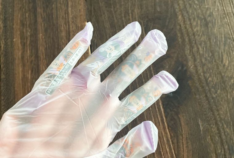 透明手袋の指先にお菓子を詰めている写真