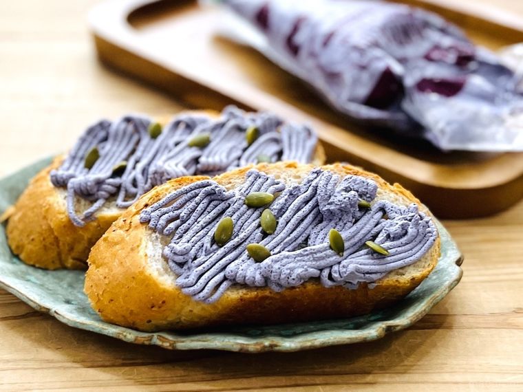 カルディのモンブランホイップクリーム 紫芋フレーバーをバゲットに絞った様子