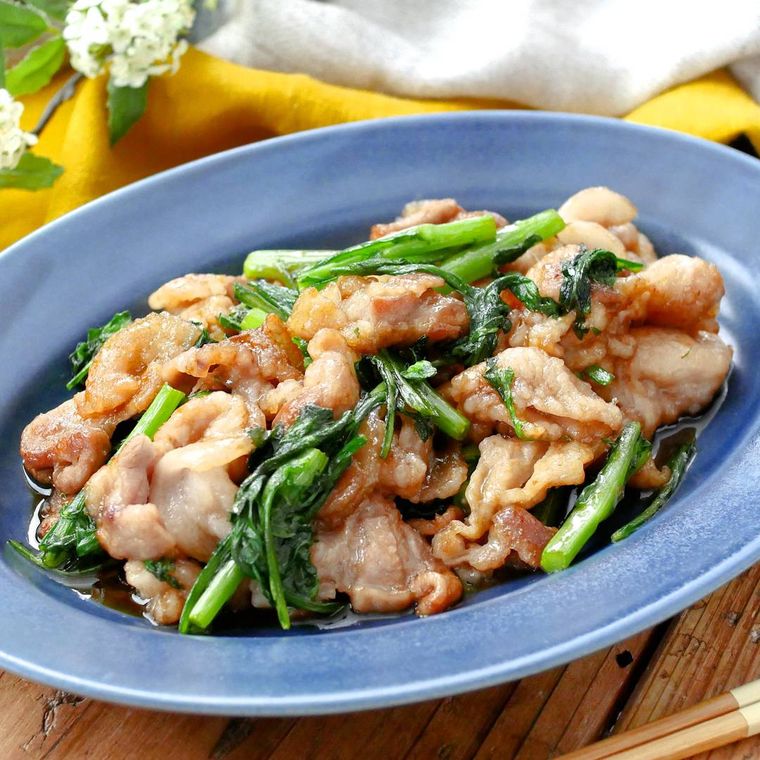 青い楕円形の皿に盛り付けた春菊と豚バラのオイスター炒め