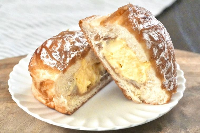 木のカッティングボードと白い皿にのったマロンクリームがトッピングされた菓子パンの断面とストライプの布