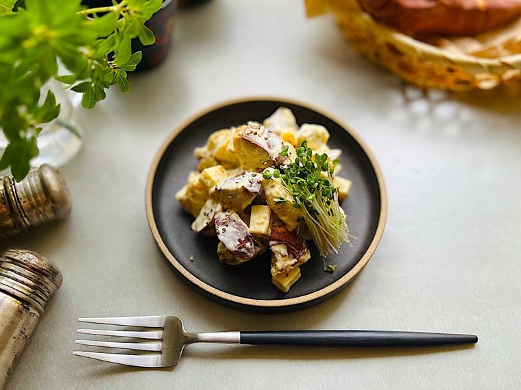 黒の器に盛ったコストコの焼き芋を使ったポテトサラダとスプラウト、周囲に置かれたスパイスとカトラリー、カゴに入った焼き芋