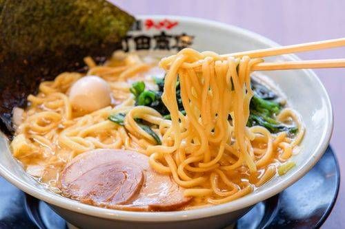 チャーシュー、卵、野菜、海苔がのったラーメンの麺を持ち上げている様子