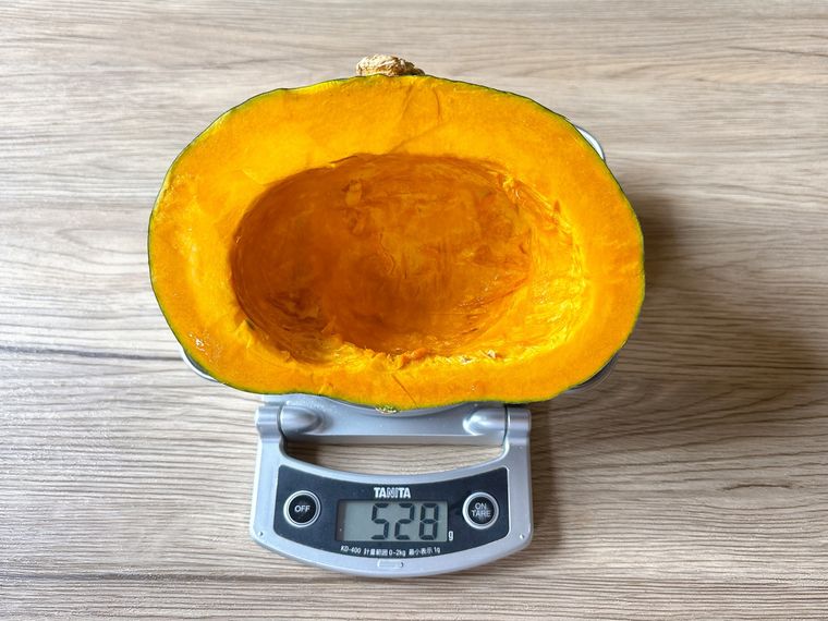 かぼちゃの種を除いた半分の重さをはかる様子