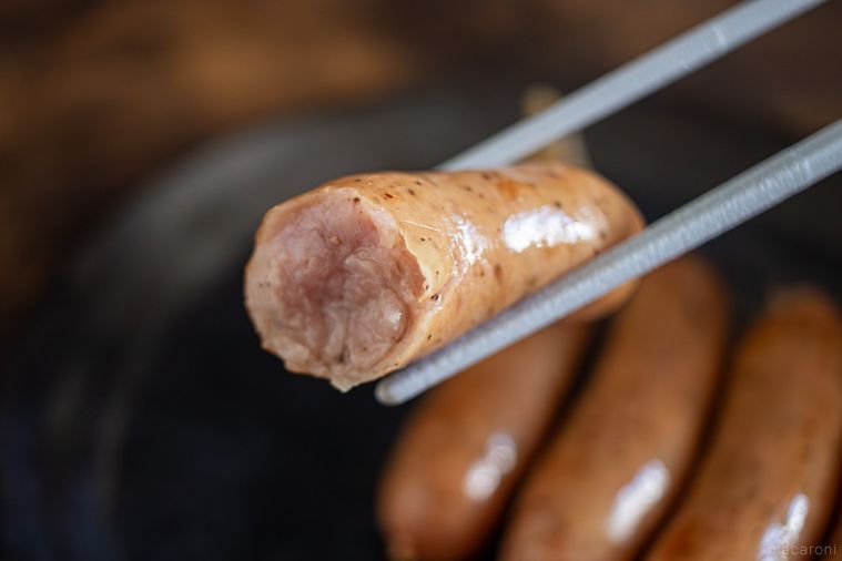 半分に割った丸大食品燻製屋 熟成あらびきウインナー ブラックペッパーを箸上げしている様子