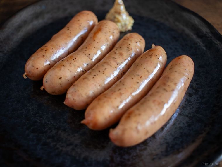 黒いお皿に焼いた燻製屋 熟成あらびきウインナー ブラックペッパー5本と粒マスタードが盛り付けられている