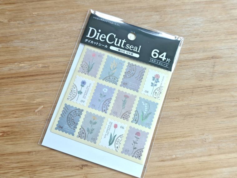 ダイカットシール 一輪の花 切手風が机の上に置いてある