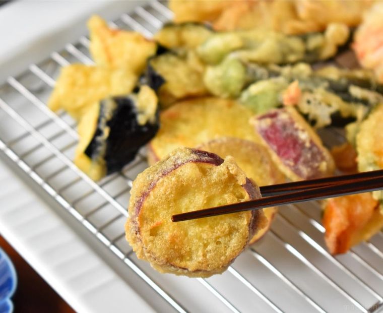 箸でつまんださつまいもの天ぷら