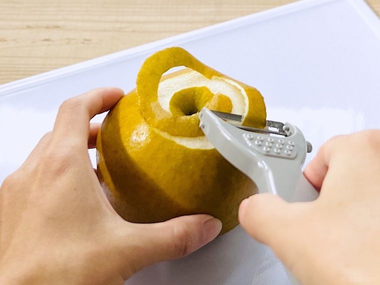 梨の皮をピーラーでむいている様子