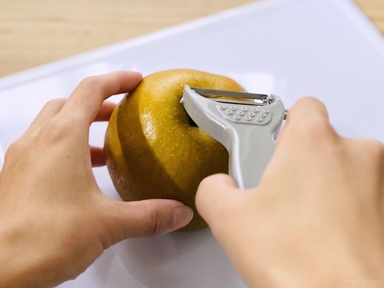 梨の上部にピーラーの刃を当てている様子