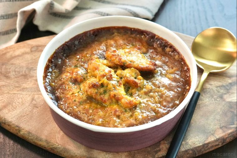 木のカッティングボードにのったコンビニの焼きカレーと金色と黒色のスプーン