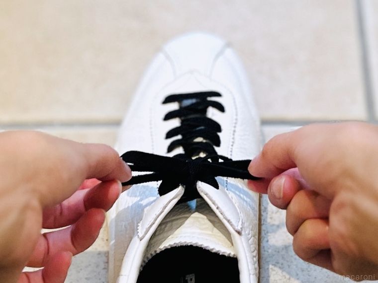 白いスニーカーに黒い靴紐を付けた様子